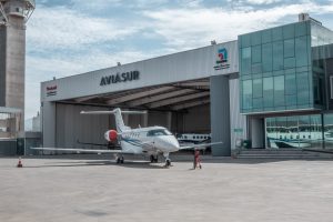 Jet ejecutivo estacionado frente al hangar de Aviasur en el aeropuerto de Santiago, con el letrero de la compañía sobre el portón