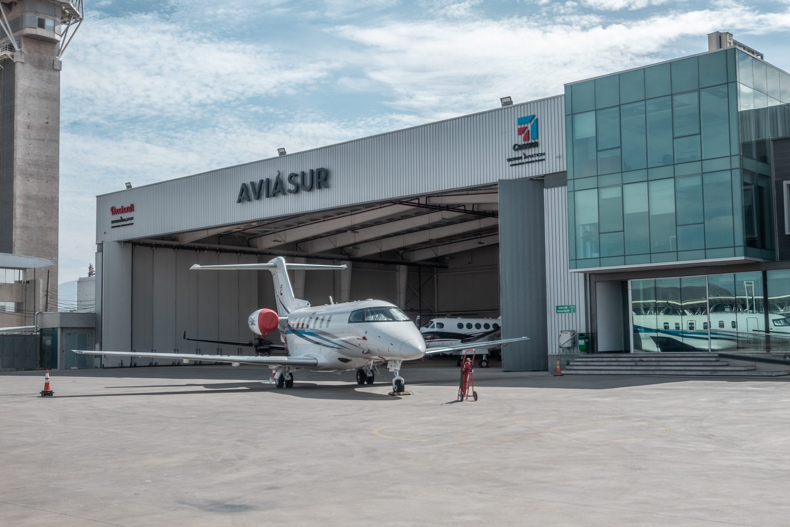 Jet ejecutivo estacionado frente al hangar de Aviasur en el aeropuerto de Santiago, con el letrero de la compañía sobre el portón