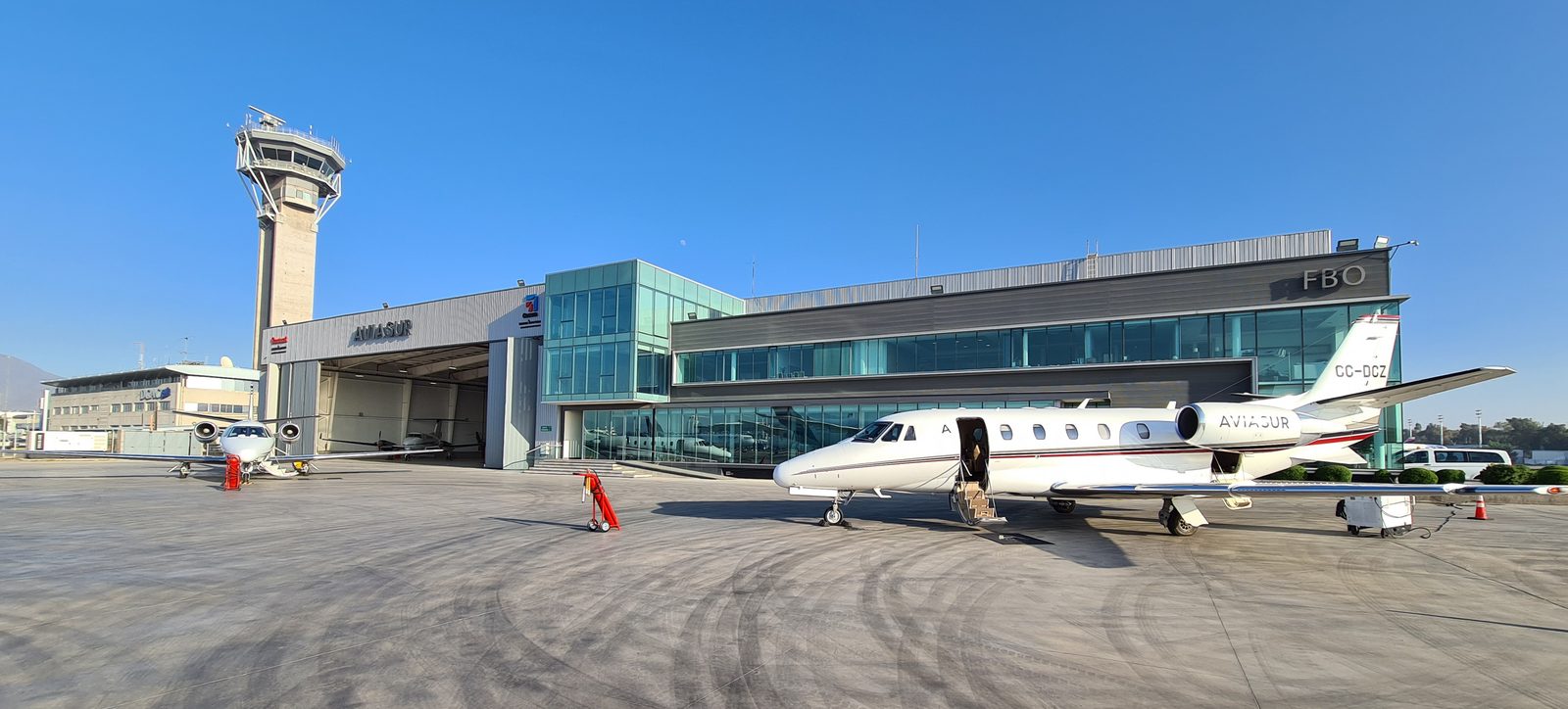 Terminal FBO de Aviasur en el aeropuerto de Santiago, con la torre de control de Pudahuel a un costado y dos jets ejecutivos estacionados en plataforma